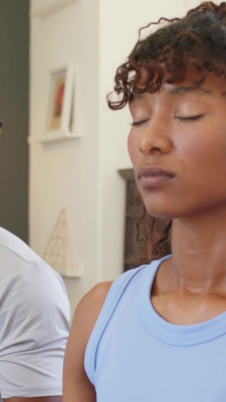 Vertical video: Entering frame man urging pair breathing at home woman blue top man gray tee shelf