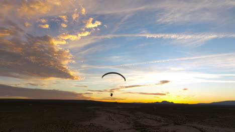 silhouette of a powered paraglider during a colorful sunset in the mojave desert