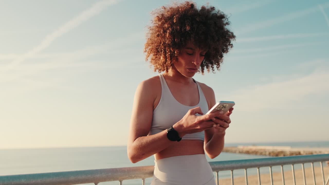 Sporty Woman Checks Phone at Beach
