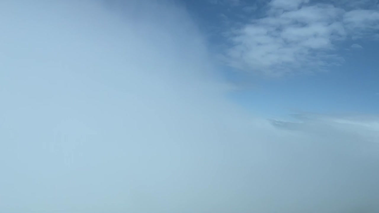 Cockpitudsigt mens man flyver gennem et hvidt skyhav i dagslys.