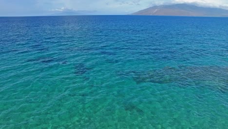 在夏威夷清<unk>的蓝水上空拍摄,背景是土地