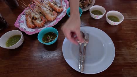 hands preparing a table with seafood and sauces.