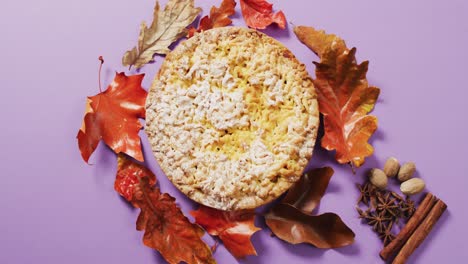 Video-of-autumn-leaves,-spices-and-pie-on-purple-background