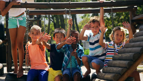 portrait of happy schoolkids waving hands in playground