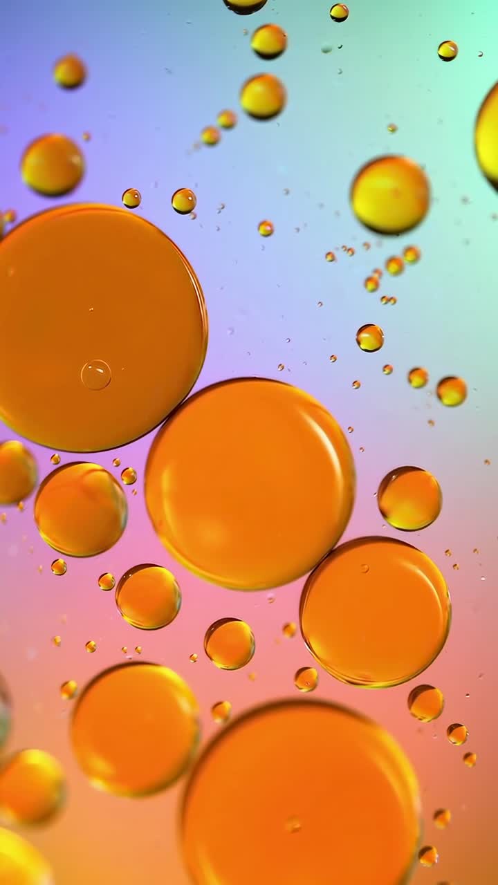 Vídeo em close-up de bolhas de óleo laranja em um plano de fundo com arco-íris, filmado de cima, Live mobile