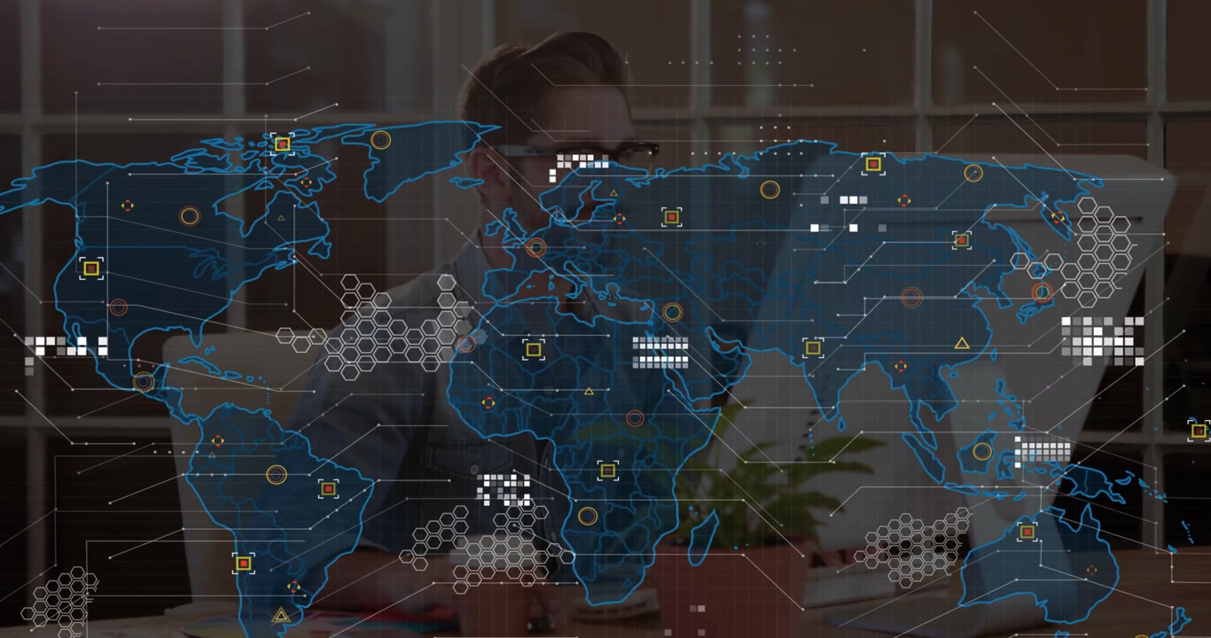 Man typing at desk, causing world map overlay expanding into tech HUD nodes, lines, analyzing data