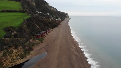 4K-Glatte-Luftaufnahme,-Die-über-Den-Rand-Des-Ozeans-Fliegt-Und-Die-Berge-Und-Sanften-Hügel-Des-Strandes-Von-Branscombe-Erblickt