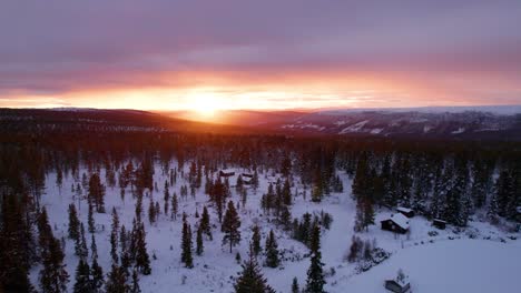 sunset in a winter mountain forest landscape with wooden cabins