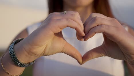 Cropped-shot-of-young-woman-making-heart-shape-with-hands.
