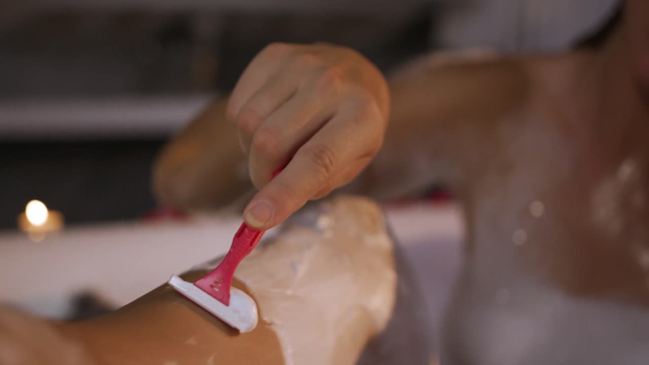 mujer caucásica afeitando la pierna en el baño en el hotel