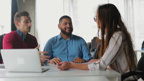 Cheerful-managers-sitting-at-table-and-discussing-business-issues.