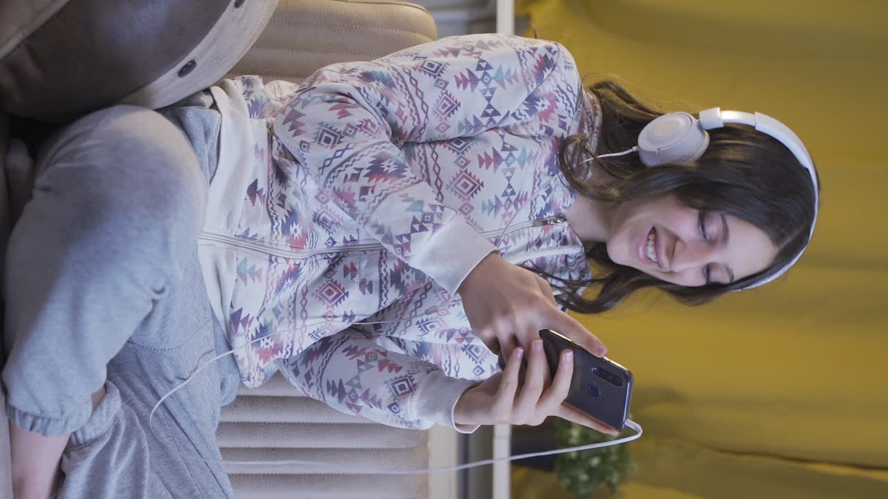 video vertical de una mujer joven enviando mensajes de texto en el teléfono con expresión feliz.