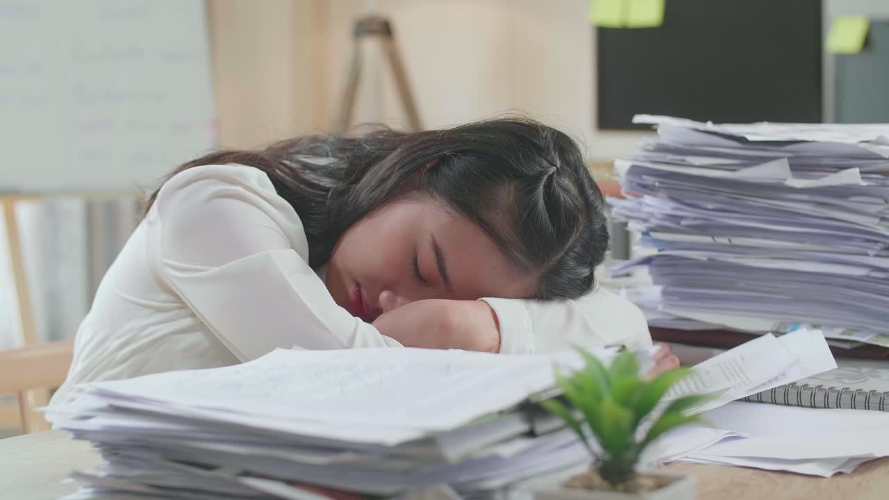 사무실에서 문서와 함께 열심히 일하기 때문에 잠을 자는 피곤한 아시아 여성의 근접