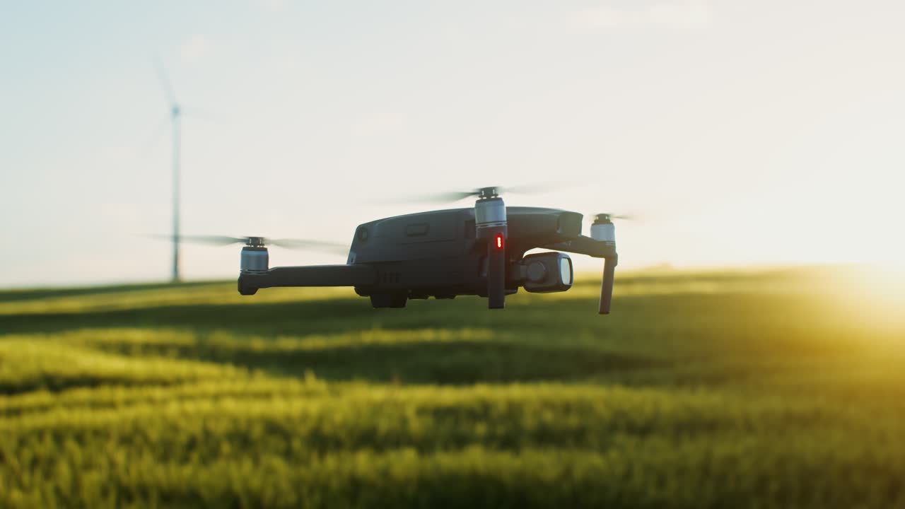 배경 에 풍차 가 있는 해가 뜨고 해가 지는 때 들판 을 날아다니는 드론