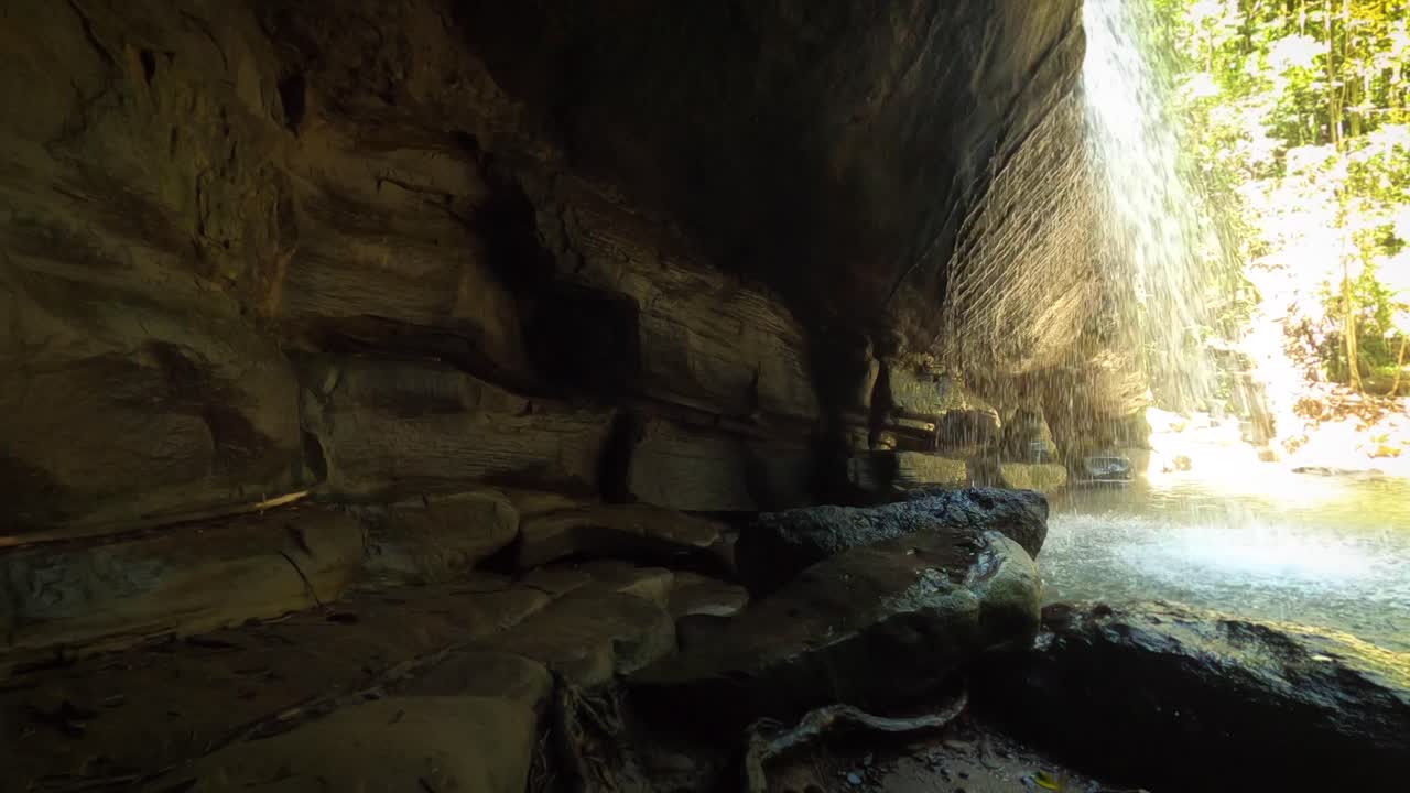 pov dentro de la cueva con vistas a la laguna y la cascada en la selva tropical en un día soleado