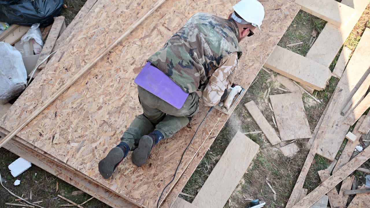 carpintero usando sierra circular para cortar tablero osb para construir una casa de marco de madera.