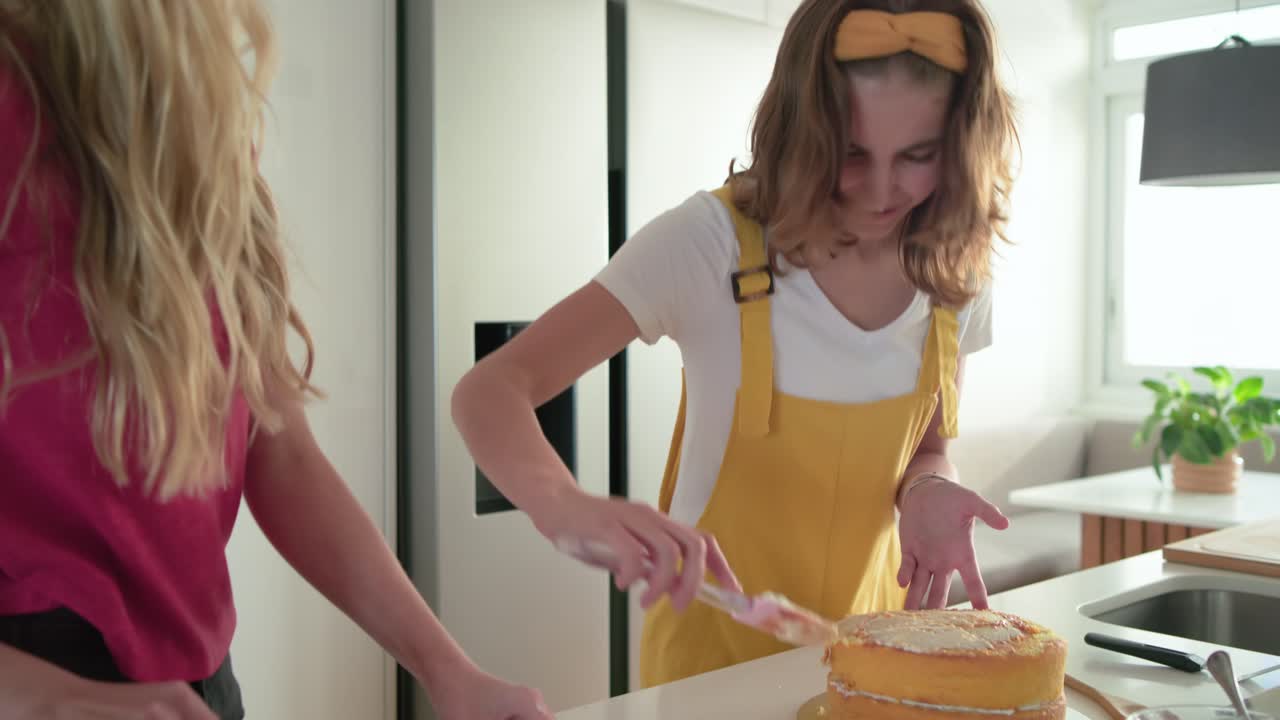 Amiche che preparano dolcetti mentre tagliano fichi e spalmano la glassa su una torta all'isola della cucina