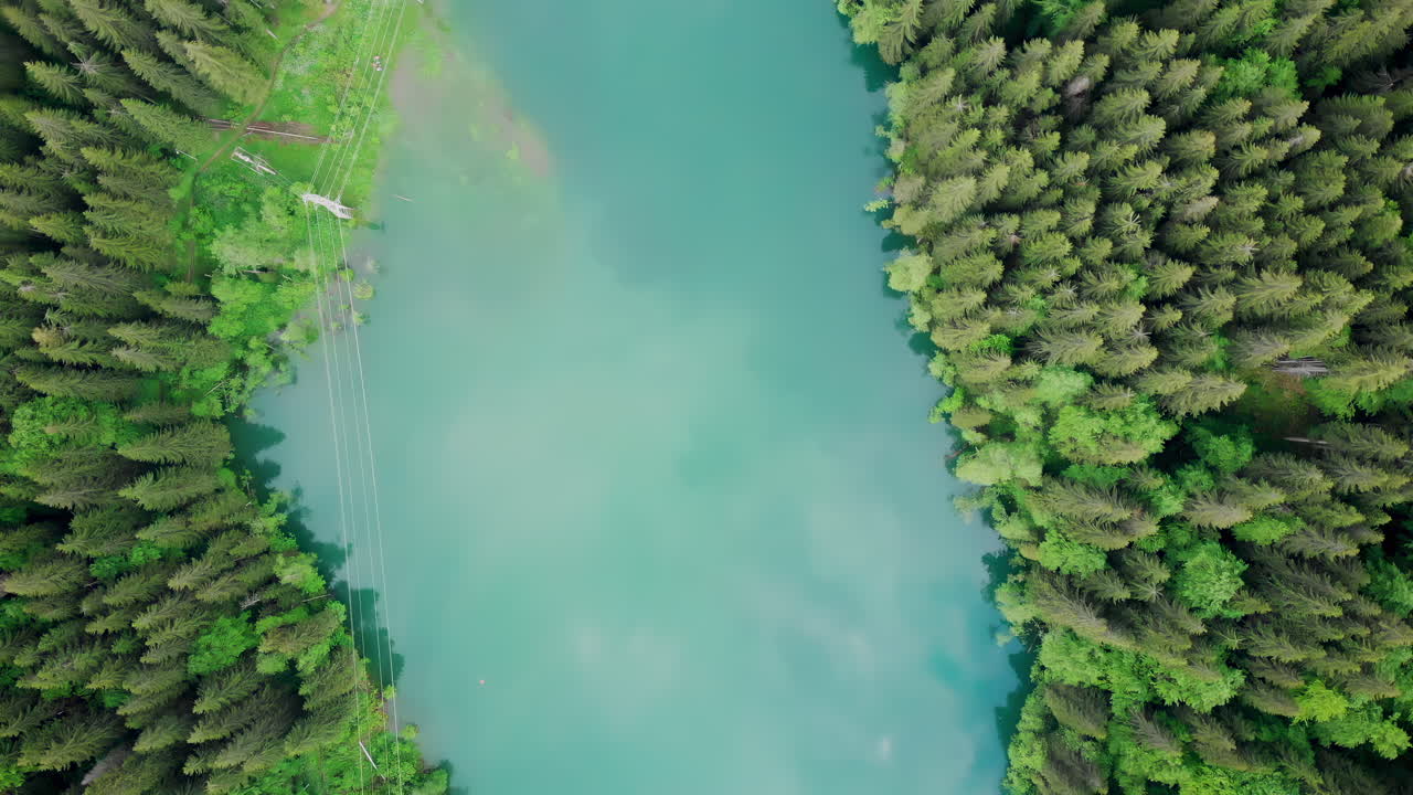 Clear turquoise water reflects the vibrant green of surrounding trees. This tranquil lake, located in a remote natural setting, invites peace and exploration in nature's embrace