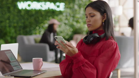 Hermosa-Joven-Mujer-De-Negocios-De-Raza-Mixta-Usando-Un-Teléfono-Inteligente-En-La-Oficina-Enviando-Mensajes-De-Texto-Navegando-Por-Mensajes-En-Un-Teléfono-Móvil-Compartiendo-Ideas-Profesionales-Disfrutando-De-Un-Lugar-De-Trabajo-Moderno