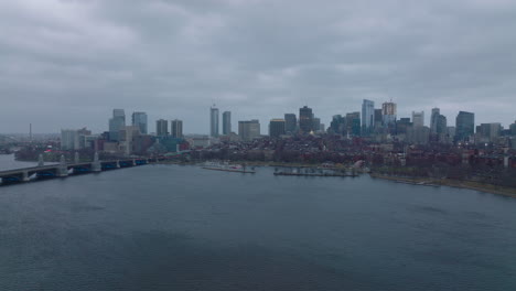 Aerial-panoramic-footage-of-rippled-Charles-river-dam-and-buildings-in-surrounding-boroughs.-Cityscape-with-skyscrapers-in-background.-Boston,-USA