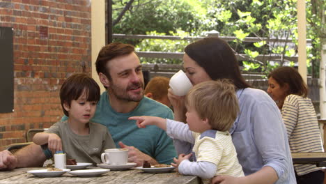 family sit at outdoor cafe table having snack shot on r3d