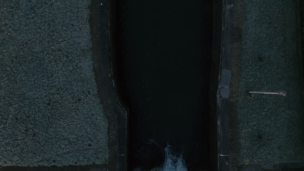 Drone shot of a river floating into another river bed during a freezing and cold morning with grass field on both sides of the river, top down shot