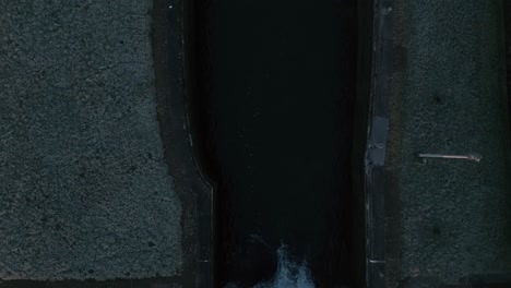 drone shot of a river floating into another river bed during a freezing and cold morning with grass field on both sides of the river, top down shot