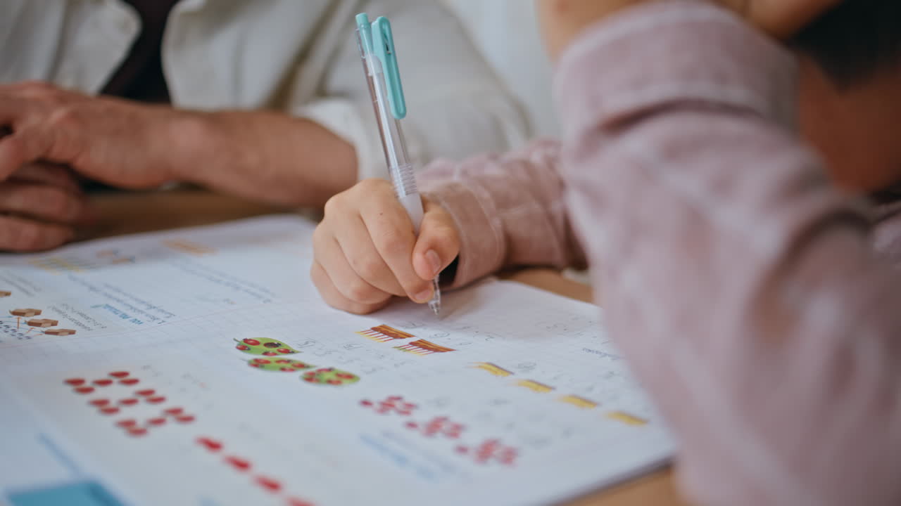 Boy hand writing homework with daddy at table closeup. Small child educating
