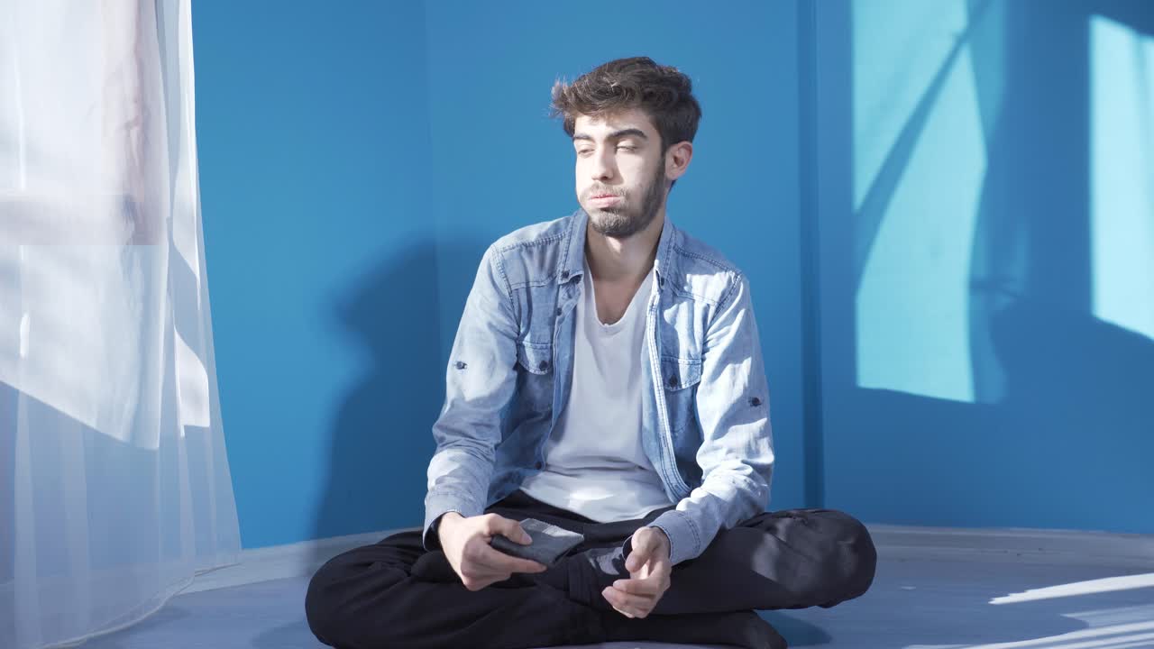 벽  ⁇ 에 앉아 있는 남자는 빈 지갑을 쳐다본다.