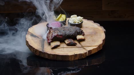 hot smoking tasty bbq ribs on a rustic wooden plate with sides of pickles medium tilt-up shot