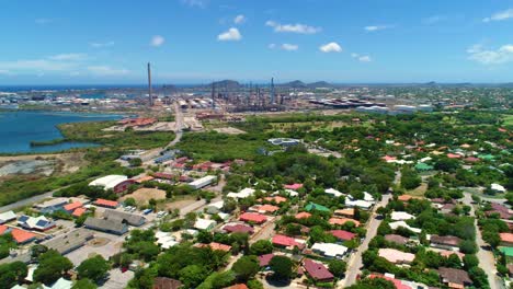 aerial dolly to oil refinery near ocean port harbor behind neighborhood suburb, curacao