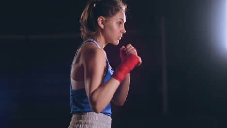 Boxeadora-Entrenando-En-Una-Habitación-Oscura-Con-Luz-De-Fondo-En-Vista-Lateral-En-Cámara-Lenta.-Disparo-De-Cámara-Steadicam