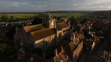 aerial view of church of saint mary with birds flying over the houses at sunset in england, uk