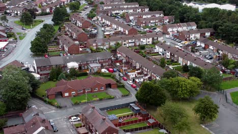 aerial view above british neighbourhood small town residential suburban property gardens and town streets descend slow