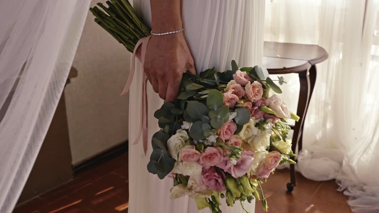 la mano de una mujer vestida de blanco sosteniendo un hermoso ramo de flores
