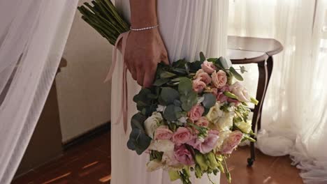 woman's hand dressed in white holding a beautiful bouquet of flowers