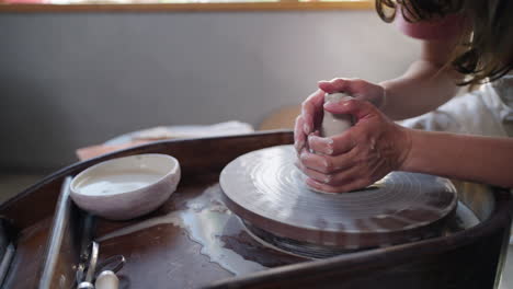 woman shaping clay on pottery wheel