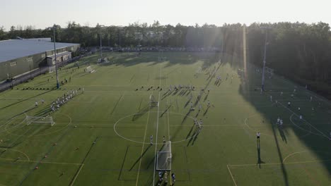 people practicing and playing on soccer field on a sunny summer day