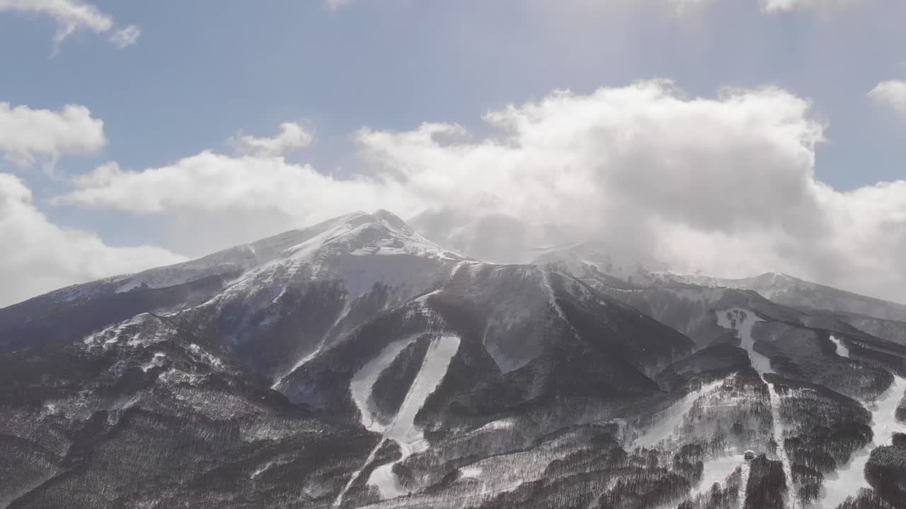 Veduta aerea panoramica che mostra cime montuose innevate e nuvole in movimento ad Aomori, Giappone.