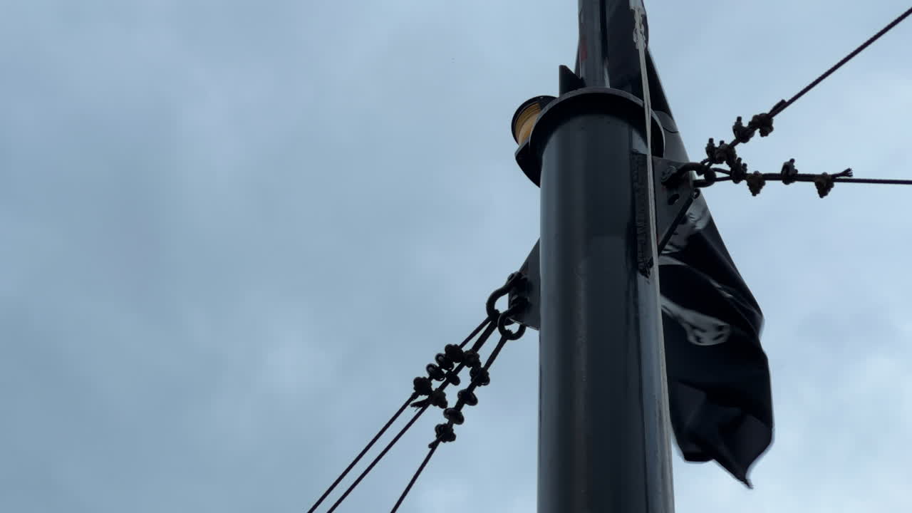 Waving Black Pirate Flag With Skull And Crossbones Symbol In Riverboat - low angle