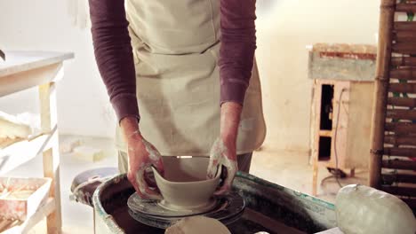 Mid-section-of-potter-making-pot