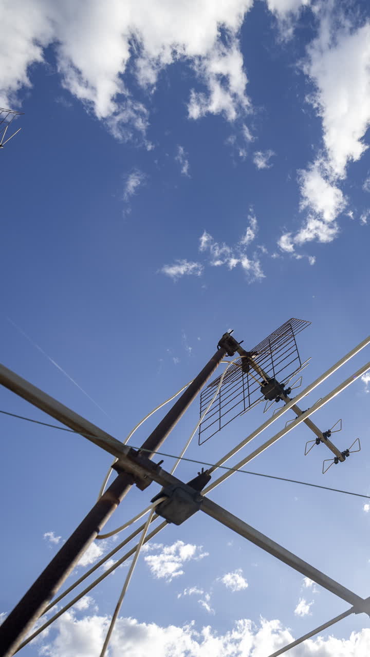 A timelapse of the sky and clouds with television aerials in the foreground