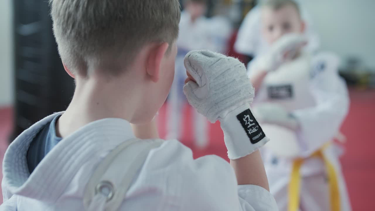 jóvenes artistas marciales con cinturones blancos y amarillos practicando técnicas de kudo con enfoque y determinación