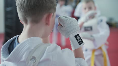 young martial artists in white gi and yellow belts practicing kudo techniques with focus and determination