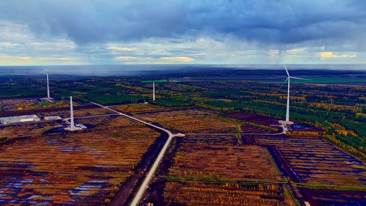 Windmills in a desolate rural field with rain in the background. Aerial