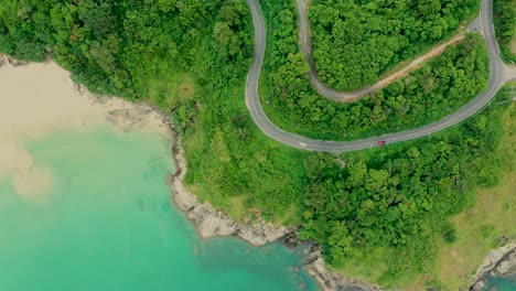 Toma-Aérea-Del-Paisaje-Natural-De-La-Bahía-De-Belleza-Con-Isla,-Conducción-De-Automóviles-Y-Mar-Claro-Con-Agua-Turquesa-En-Phuket