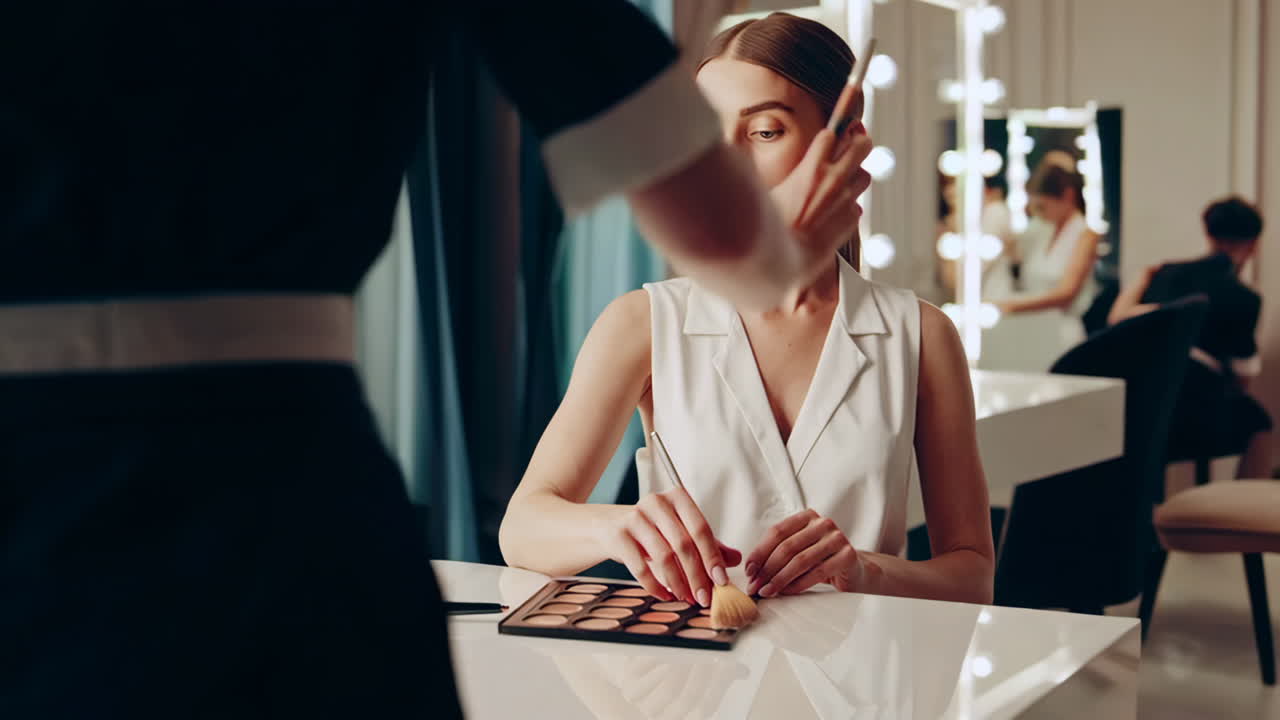 메이크업 아티스트가 모델에게 메이크업을 하고 있습니다.