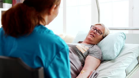 in nursing home old sick lady lying in bed talks with a female nurse