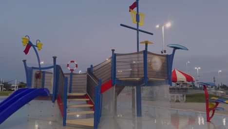 camera moves slowly toward vibrant water play structure at empty pool, captured in slow motion