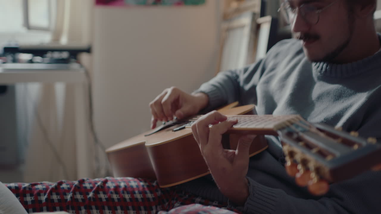 Ragazza che riposa sul letto e ascolta il fidanzato suonare la chitarra